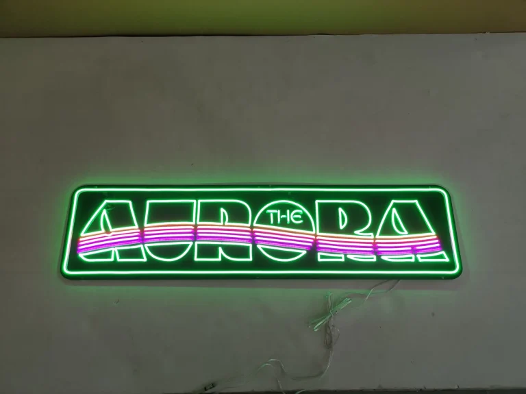 Green LED neon sign reading The Aurora with pink and orange lines displayed on a wall in Australia