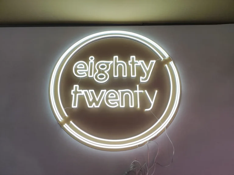 White LED neon sign displaying eighty twenty in a circular design suitable for a modern business interior