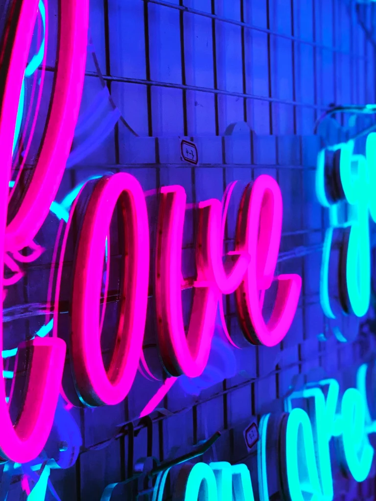 Pink and blue LED neon sign spelling 'Love You More' on a dark background Australia