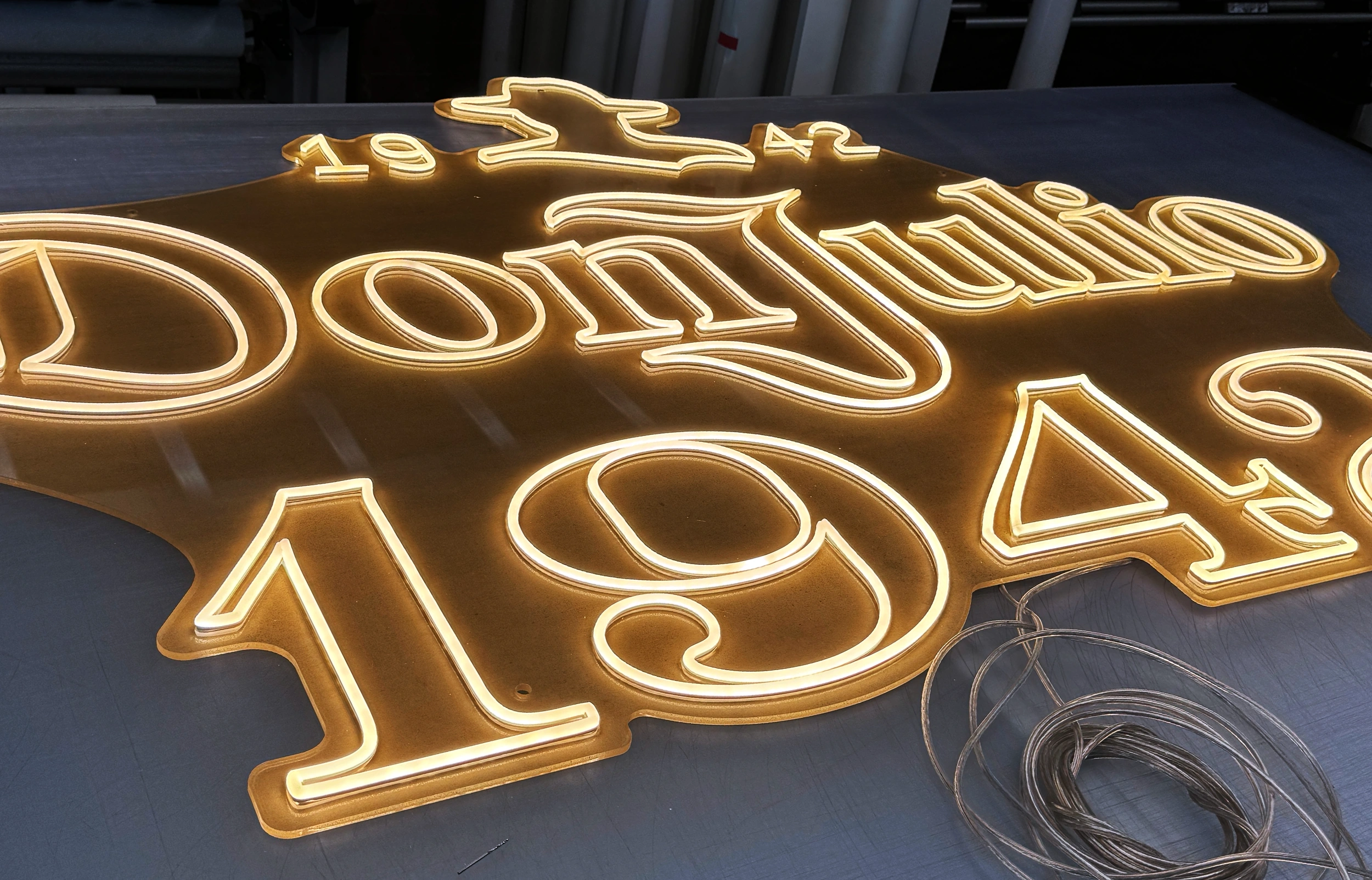 Warm white LED neon sign reading Don Julio 1942 on gold acrylic backing in production
