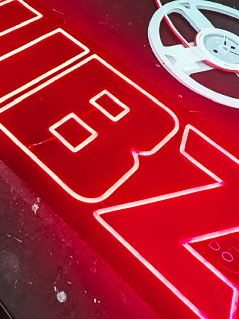 Close-up of a red LED neon sign with partially visible letters showing Sydney custom manufacturing