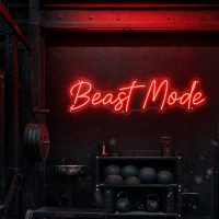 Red 'Beast Mode' neon sign mounted on a dark, moody training space wall, with cinematic lighting.