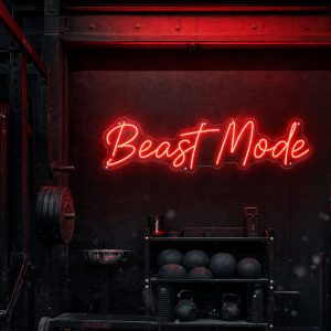 Red 'Beast Mode' neon sign mounted on a dark, moody training space wall, with cinematic lighting.