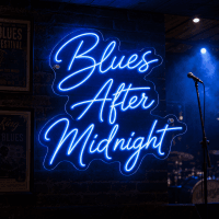 Blues After Midnight neon sign glowing blue on wall