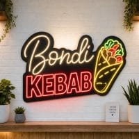 Bondi Kebab LED neon sign on clear acrylic backing mounted on white brick wall