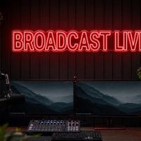 Broadcast Live Neon Sign Broadcast Live LED neon sign in red in dark streaming setup with premium monitors