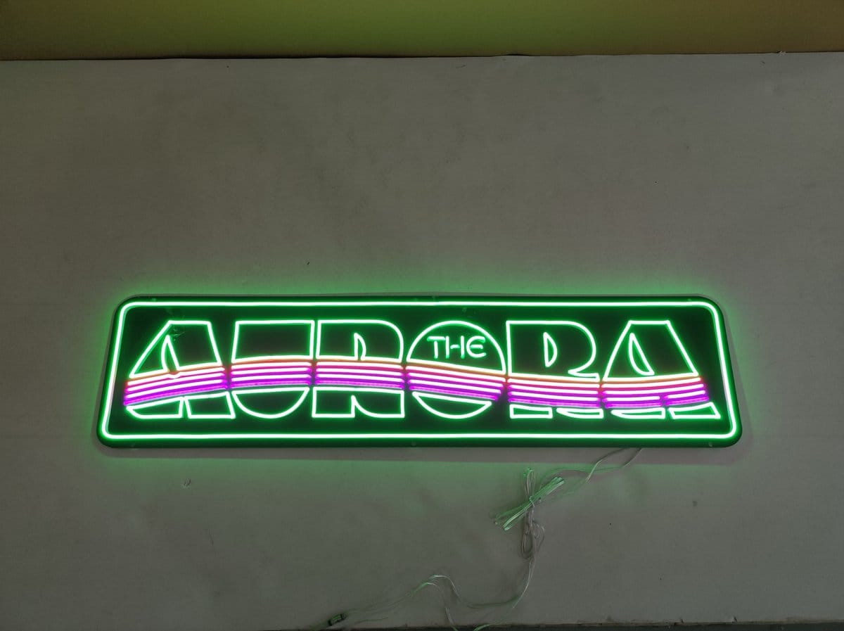 Custom neon sign displaying AURORA with colorful wave design and green border lighting in Australia