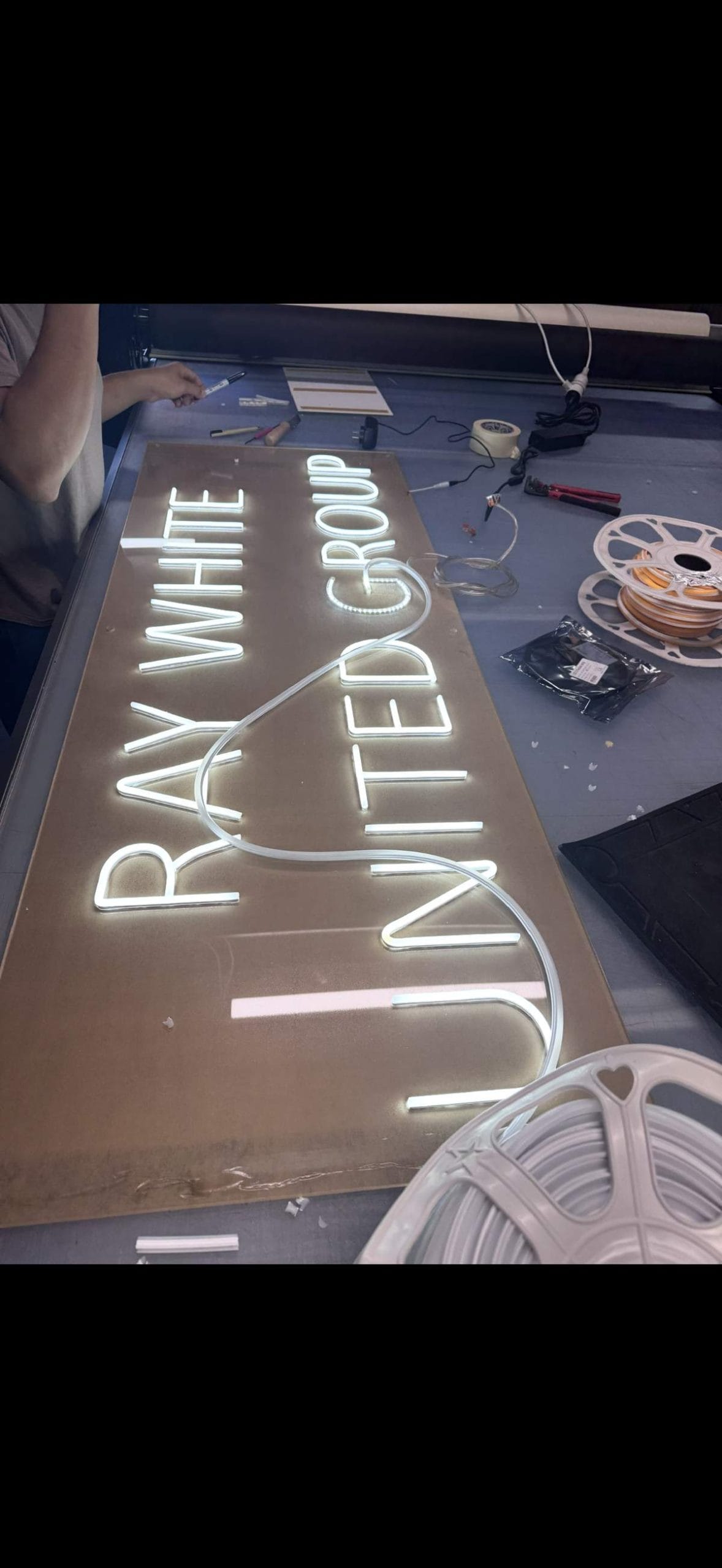 Custom neon sign reading Ray White United Group being made in Australia workshop