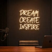 Dream Create Inspire LED neon sign in warm white script in minimalist luxury office with soft cinematic glow
