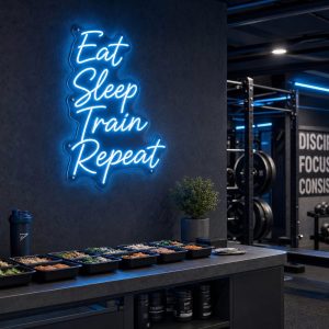 An Ice Blue 'Eat Sleep Train Repeat' neon sign mounted on a dark, moody training space wall, with cinematic lighting.