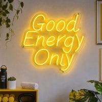 A bright yellow 'Good Energy Only' neon sign mounted on a dark wall in a modern wellness lounge, with soft ambient lighting.