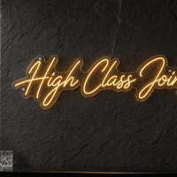 High Class Joint LED Neon Sign - warm golden cursive script on dark stone wall bar setting with crystal decanters