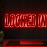 Locked In LED neon sign in red in dark focused creator setup with cinematic desk scene