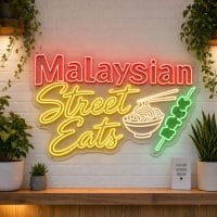 Malaysian Street Eats LED neon sign on clear acrylic backing mounted on white brick wall