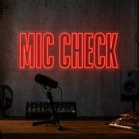 Mic Check LED neon sign in red in industrial creator setup with dark concrete wall