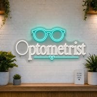 Optometrist LED neon sign with glasses icon on clear acrylic backing mounted on white brick wall