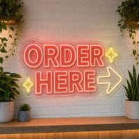 Order Here LED neon sign on clear acrylic backing mounted on white brick wall