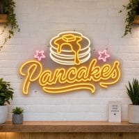Pancakes LED neon sign on clear acrylic backing mounted on white brick wall