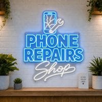 Phone Repairs Shop LED neon sign with cracked screen phone icon on clear acrylic backing mounted on white brick wall