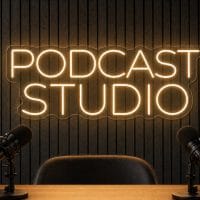 Podcast Studio LED neon sign in warm white on charcoal acoustic panel wall with studio microphones