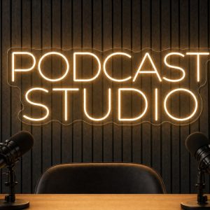 Podcast Studio LED neon sign in warm white on charcoal acoustic panel wall with studio microphones