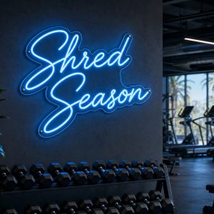 Ice Blue 'Shred Season' neon sign mounted on a dark wall in an LED-lit fitness room, with cinematic lighting and a realistic glow.
