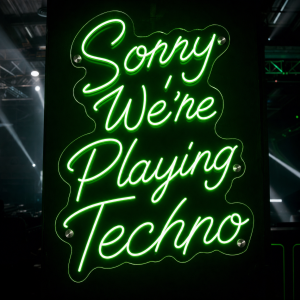 Sorry We're Playing Techno LED neon sign glowing in a music venue