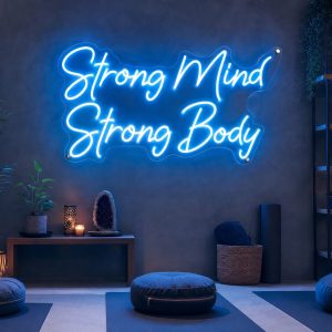 An Ice Blue neon sign displaying 'Strong Mind Strong Body' mounted on a dark grey wall in a modern, moody training space, with cinematic lighting.