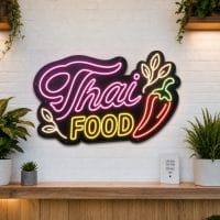 Thai Food LED neon sign on clear acrylic backing mounted on white brick wall
