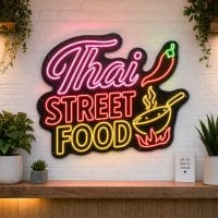 Thai Street Food LED neon sign on clear acrylic backing mounted on white brick wall